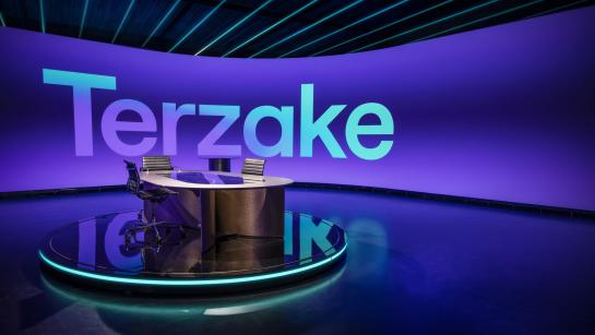 Terzake-studio met interviewtafel en het programmalogo op de paarse ledwand